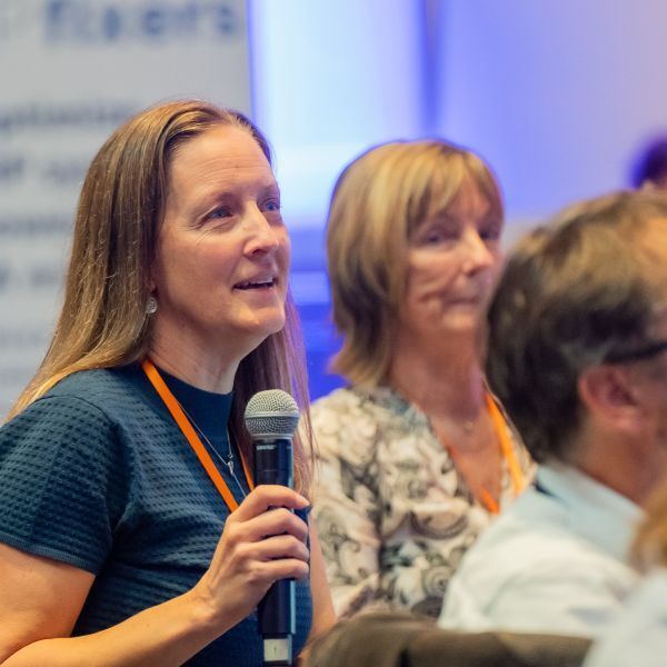 three people discuss sap while holding laptop